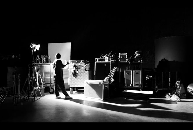 Behind the shooting of video online commercial production and film crew team working and setting light or camera or soft box and equipment set up in big studio in silhouette style