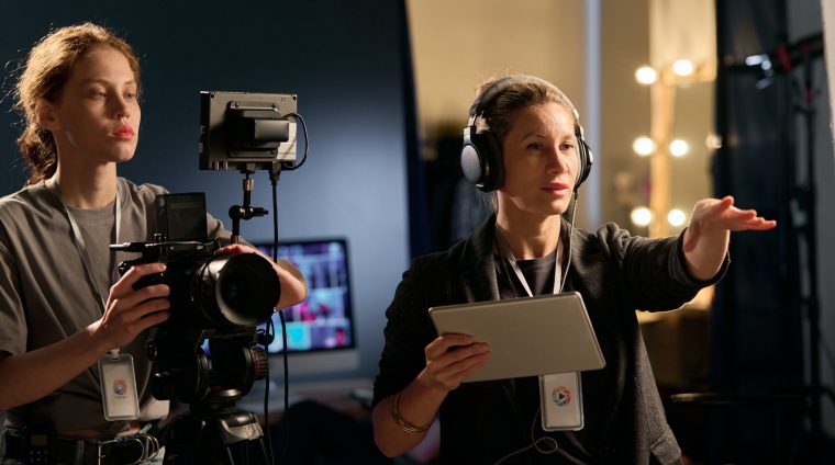 Waist up portrait of female director giving instructions on set during film production copy space